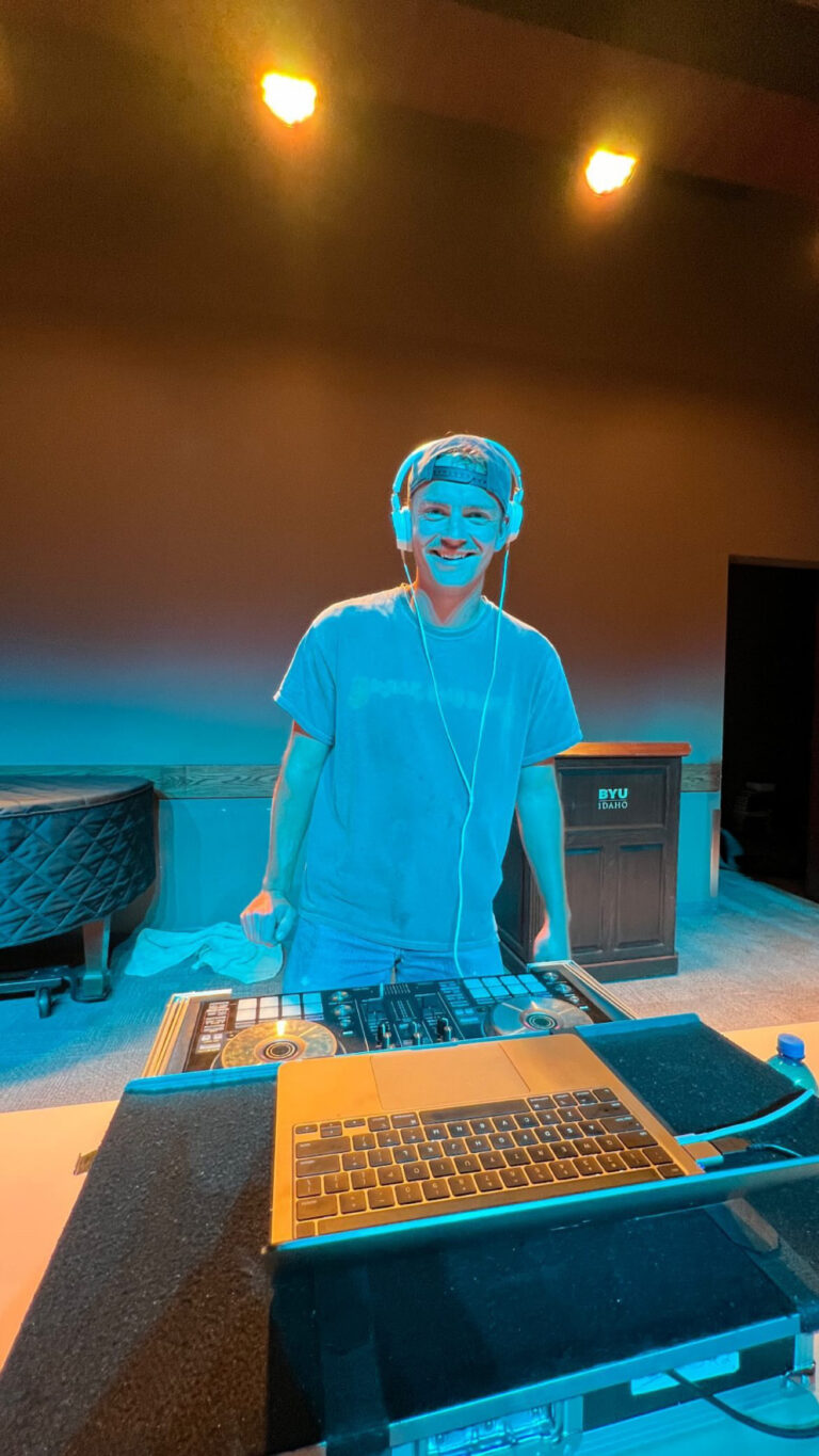 DJ with headphones at A & B Productions event, vibrant lighting, professional music setup.