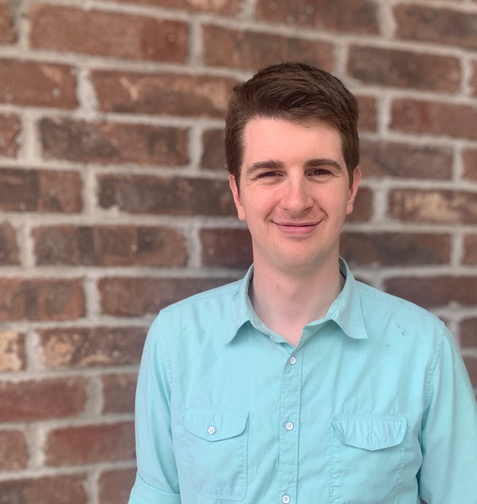 Professional portrait of a young man in front of a brick wall, representing A & B Productions.