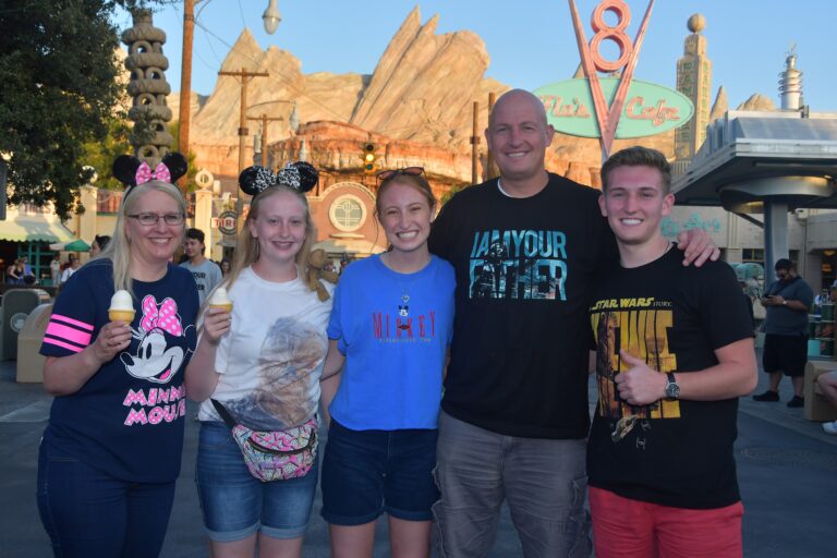 Group of five smiling people at Disneyland, enjoying a fun day out.