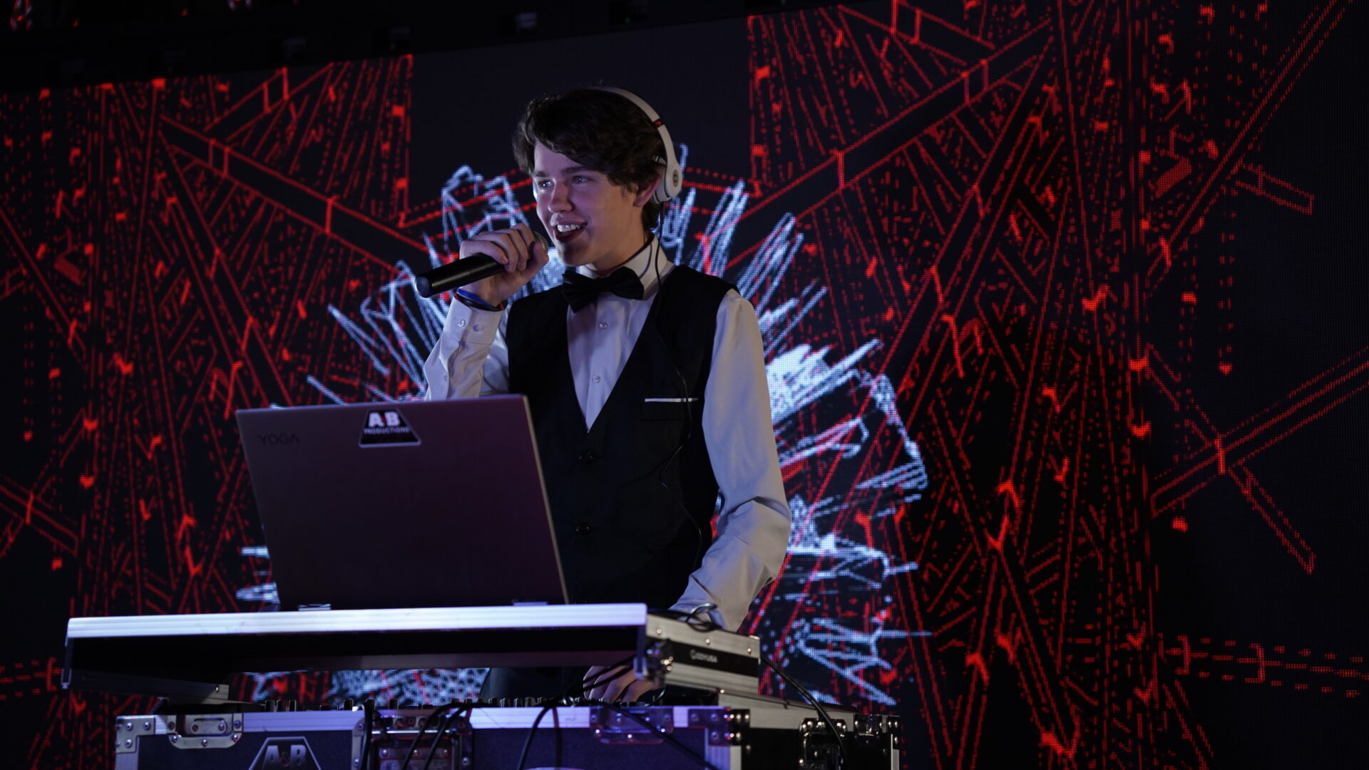 DJ performing live at A & B Productions with vibrant digital background.