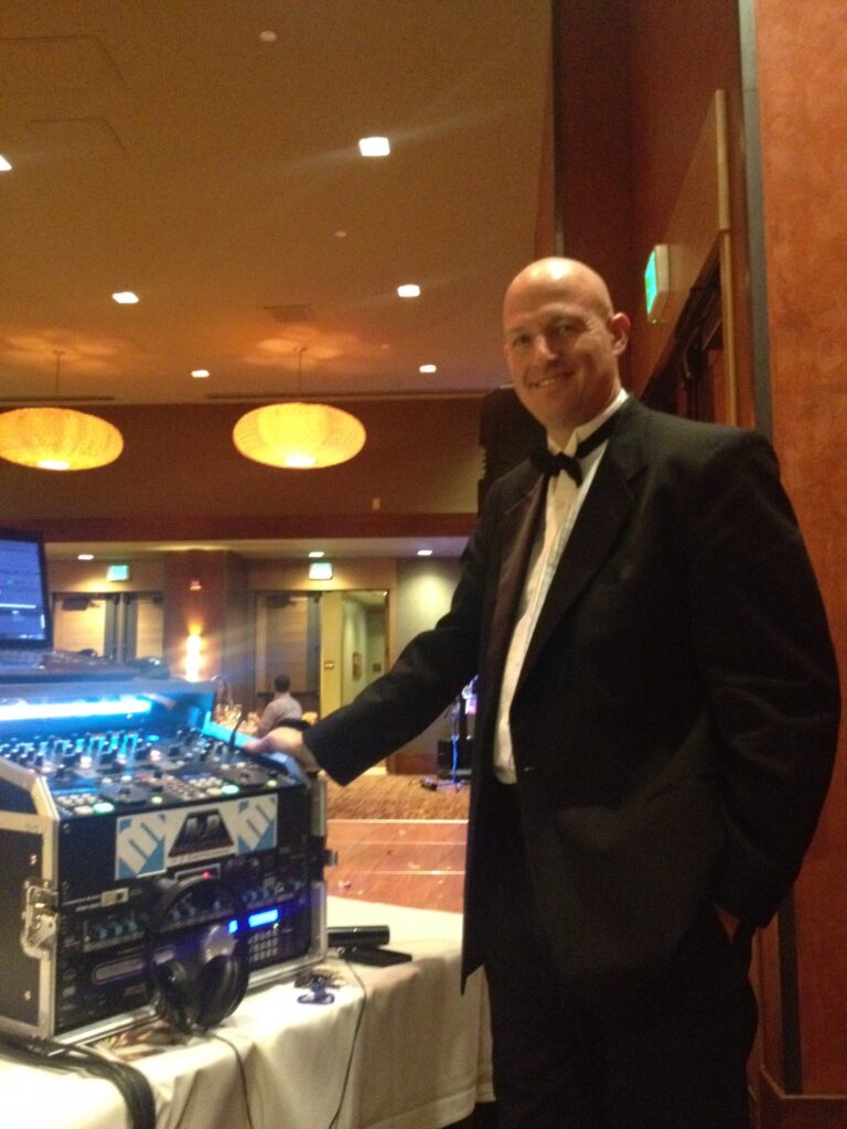 DJ performing at a formal event, showcasing professional sound equipment and entertainment services.