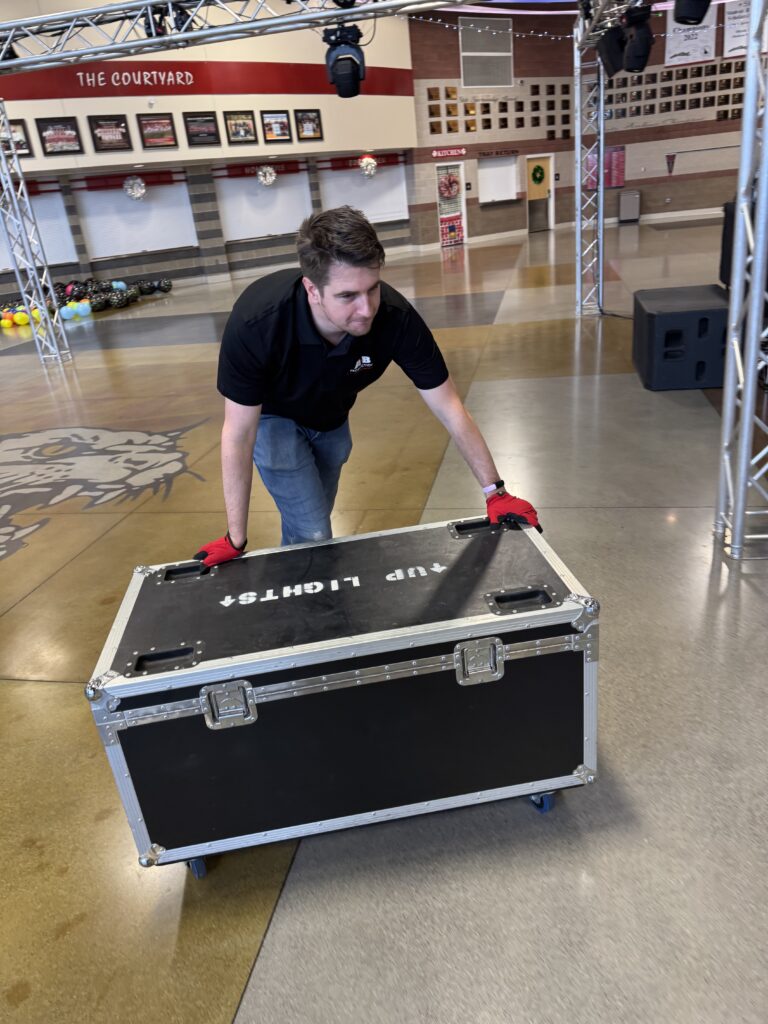 A technician preparing audio-visual equipment at A & B Productions event.