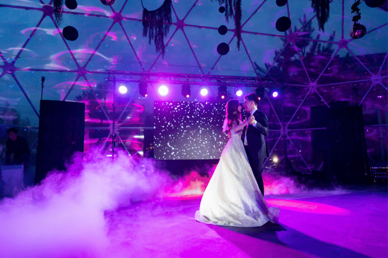 Wedding dance at A & B Productions with colorful stage lighting and fog effects.