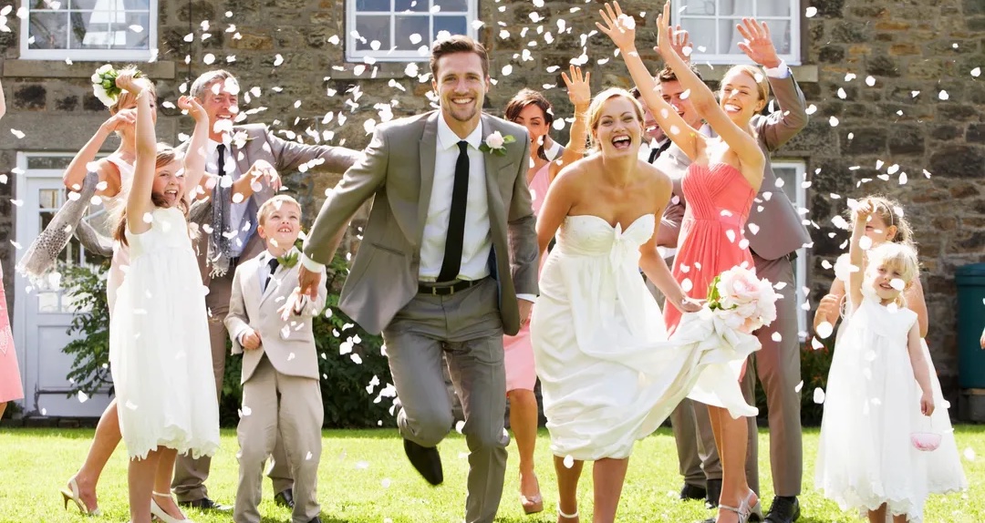 Wedding celebration with joyful bride, groom, and guests outdoors.