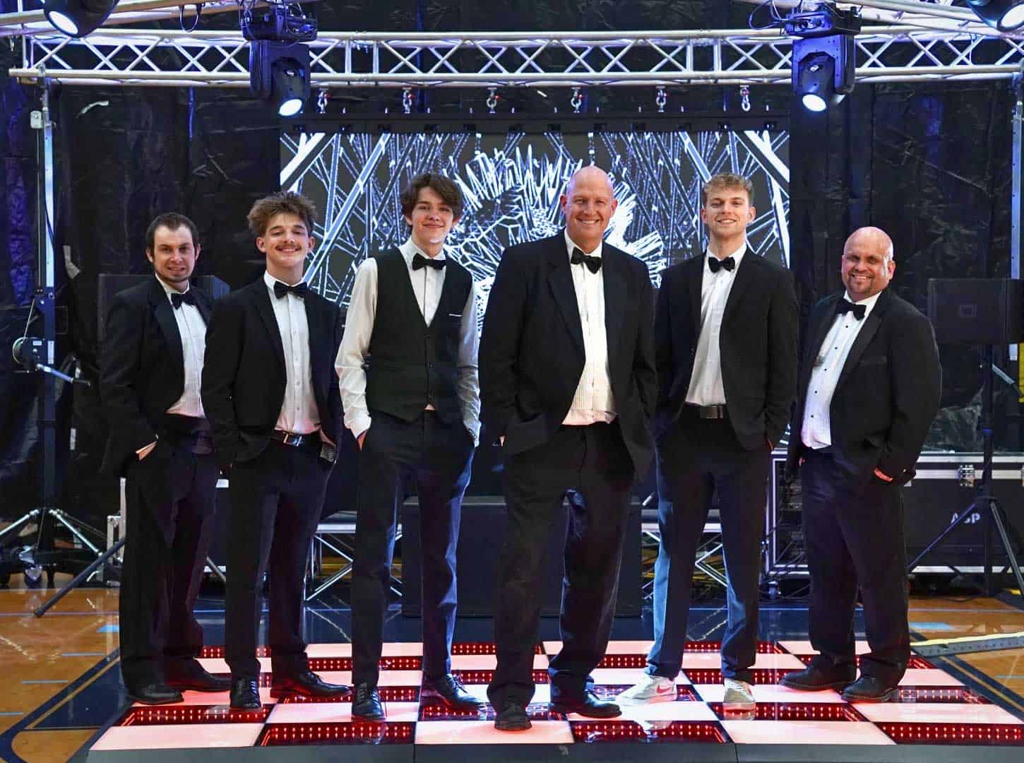 Elegant event performers in formal tuxedos on stage at A & B Productions.